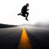 man jumping above gray and yellow concrete road at daytime