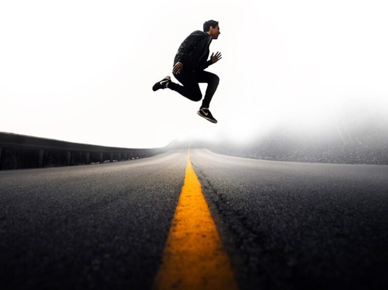 man jumping above gray and yellow concrete road at daytime